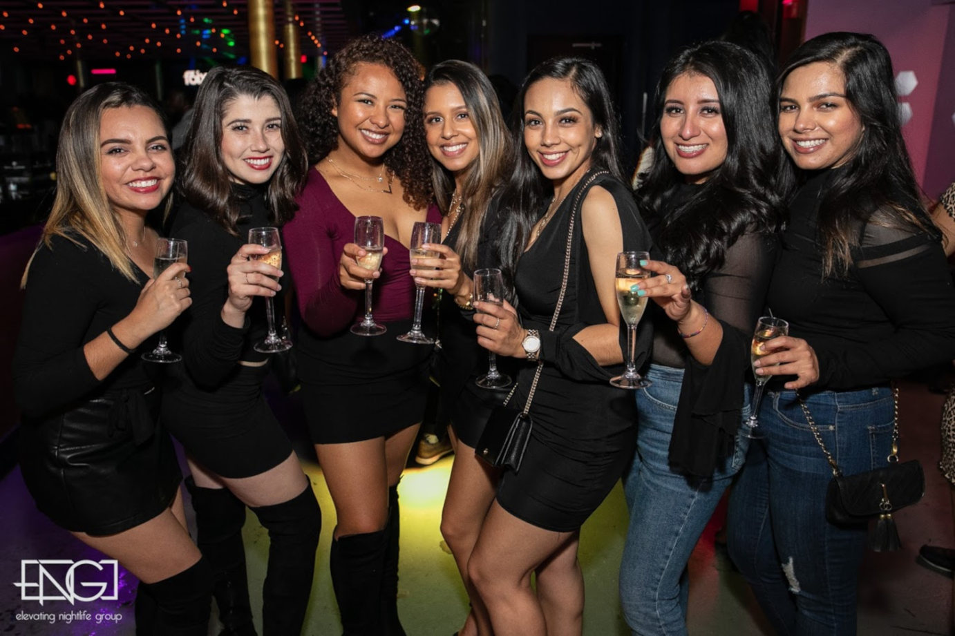 Seven girls in the club posing for a photo